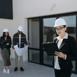 Architects in hard hats examining construction plans at a building site.