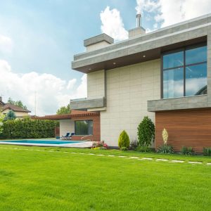 Sleek modern house with swimming pool and lush lawn, perfect for luxury living.